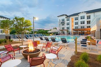 A patio with a fire pit and chairs around a pool